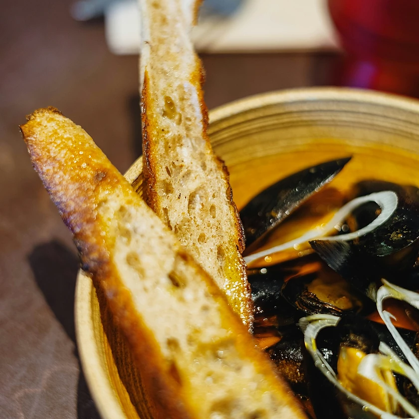 Moules dans une sauce crémeuse coco curry, servies avec du pain grillé